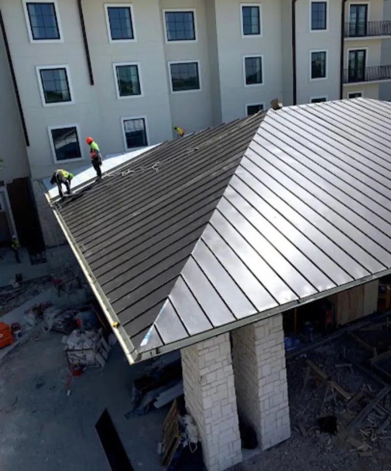 Crew installing standing seam metal roof panels on a commercial project in Meredith